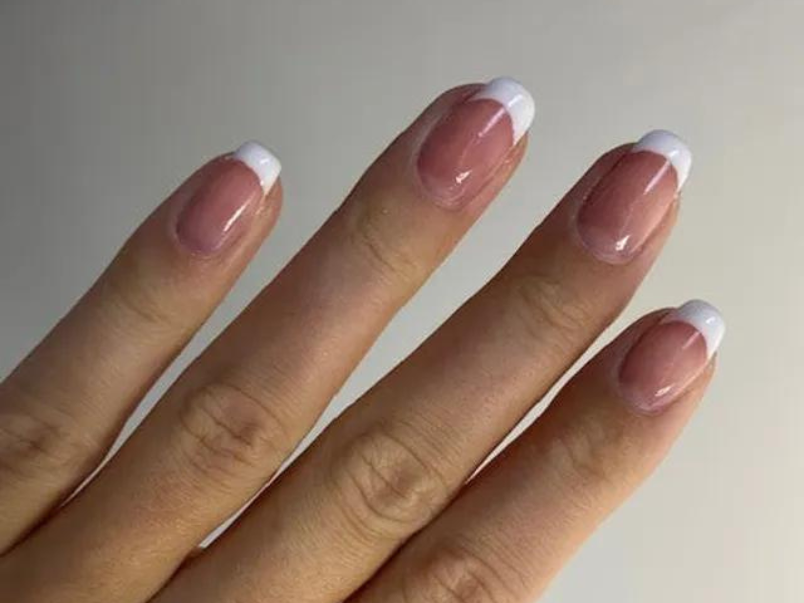 Fingers with a French manicure on white background.
