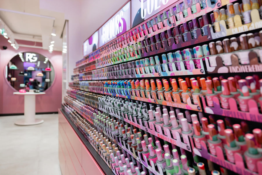 Rows of colorful nail polish bottles in a store, with a mirror in the background.