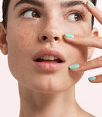 Close-up of a woman with Pink Gellac Melted Mint manicured nails near her face.