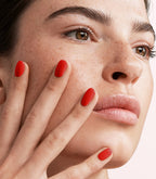 Close-up of a woman with Pink Gellac 108 Lady in Red manicured nails near her face.