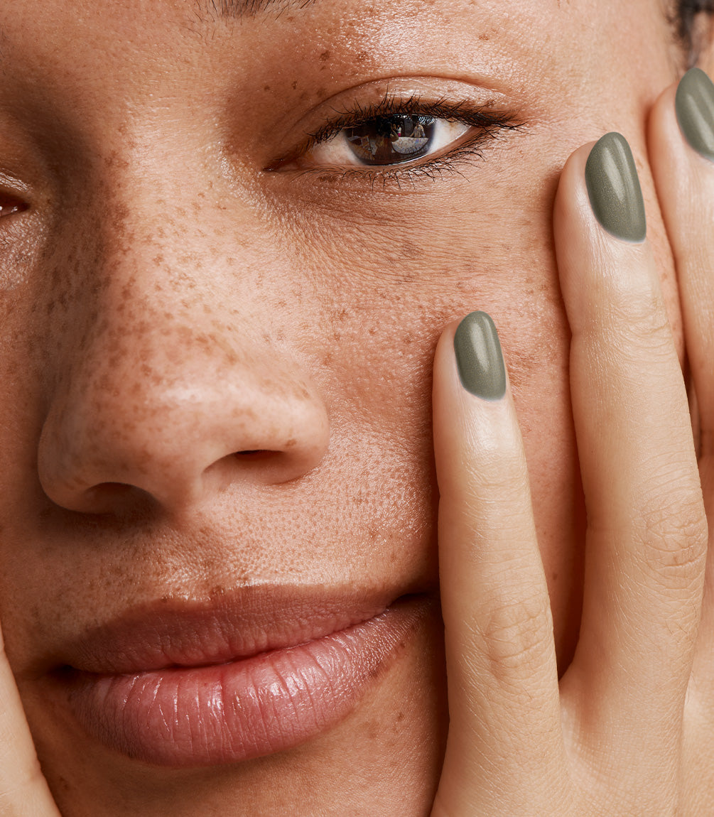 Close-up of a woman with Pink Gellac 115 Army Green manicured nails near her face.