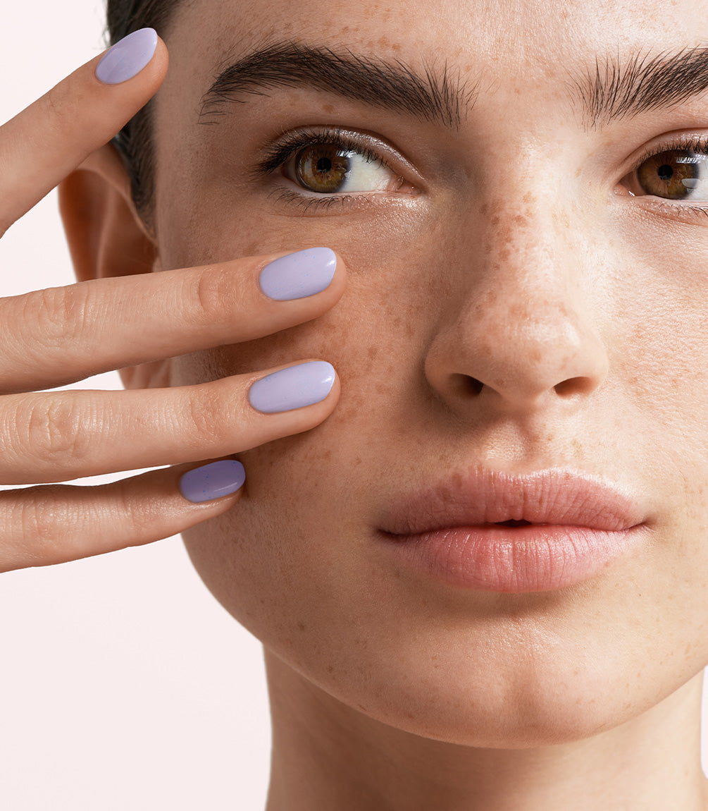 Close-up of a woman with Pink Gellac 186 Precious Lila manicured nails near her face.