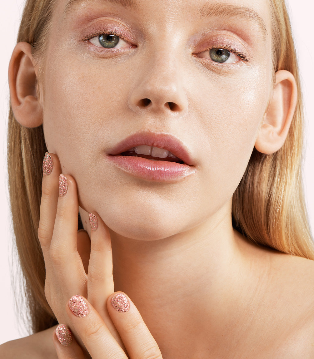 Close-up of a woman with Pink Gellac 197 Golden Glam manicured nails near her face.