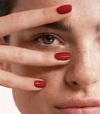 Close-up of a woman with Pink Gellac 235 Ruby Red manicured nails near her face.