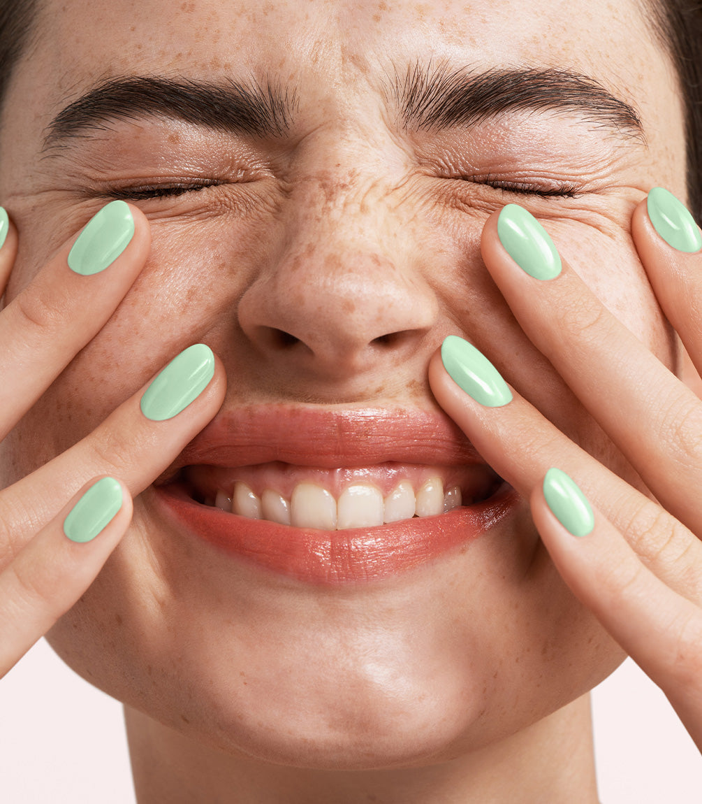 Close-up of a woman with Pink Gellac 347 Soft Jade manicured nails near her face.