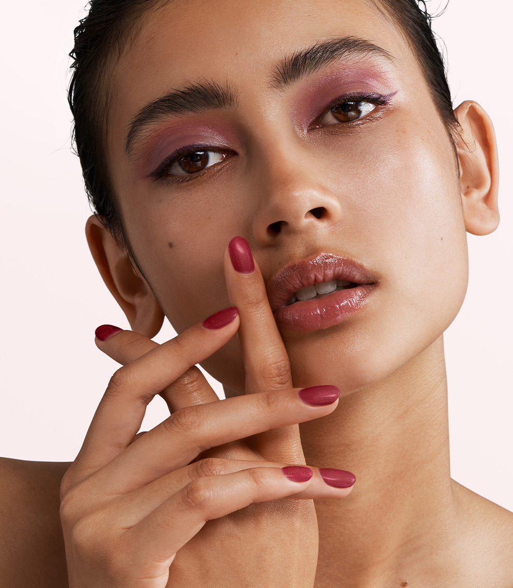 Close-up of a woman with Pink Gellac 354 Merlot Red manicured nails near her face.