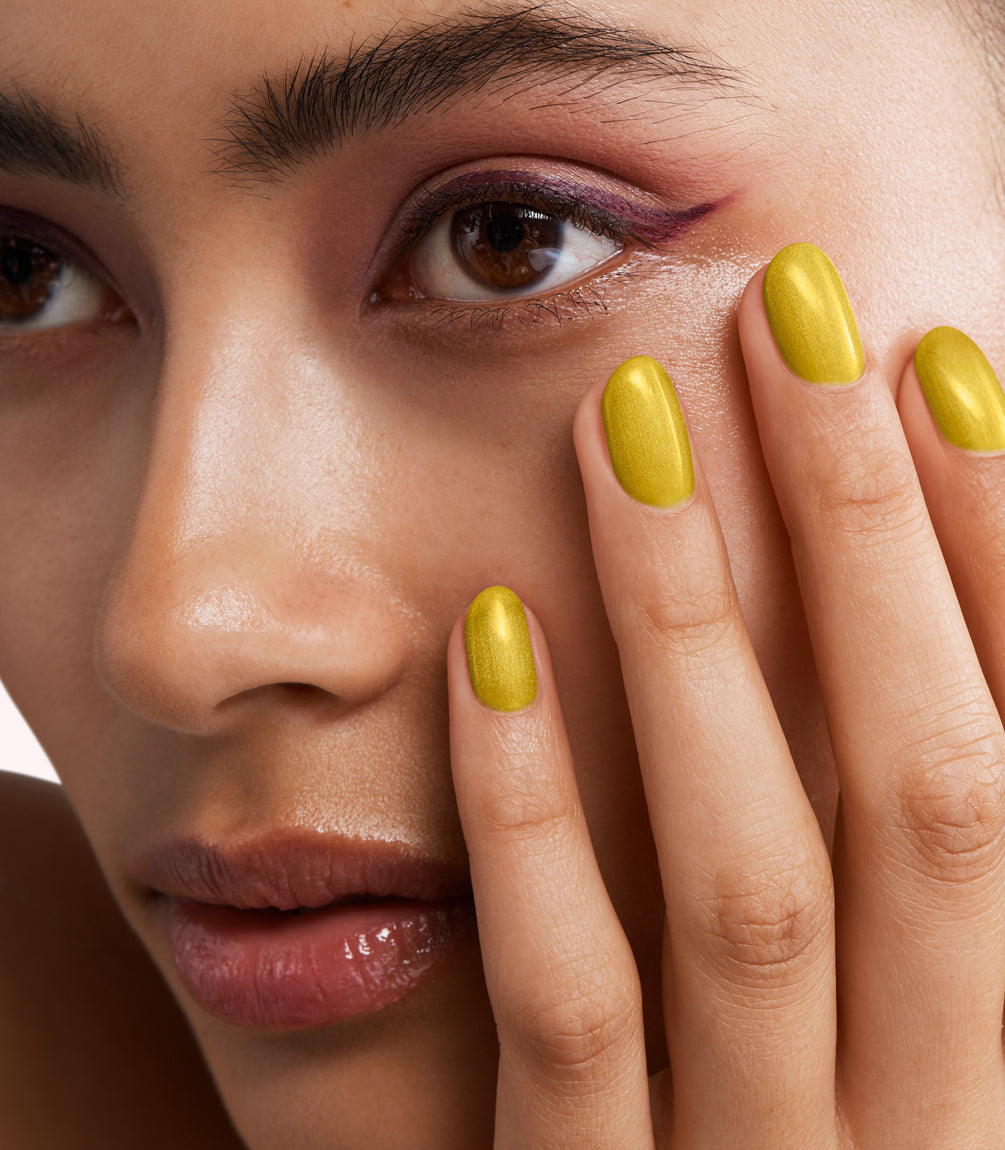 Close-up of a woman with Pink Gellac 415 Graced Gold manicured nails near her face.
