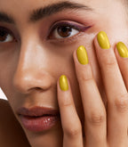 Close-up of a woman with Pink Gellac 415 Graced Gold manicured nails near her face.
