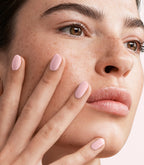 Close-up of a woman with Pink Gellac 419 Marshmallow Nude manicured nails near her face.