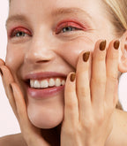 Close-up of a woman with Pink Gellac 420 Sugared Cinnamon manicured nails near her face.