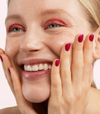 Close-up of a woman with Pink Gellac 438 Sparkling Rouge manicured nails near her face.