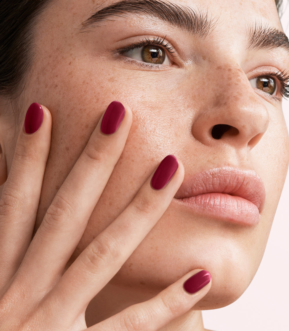 Close-up of a woman with Pink Gellac 439 Berry Sheen manicured nails near her face.