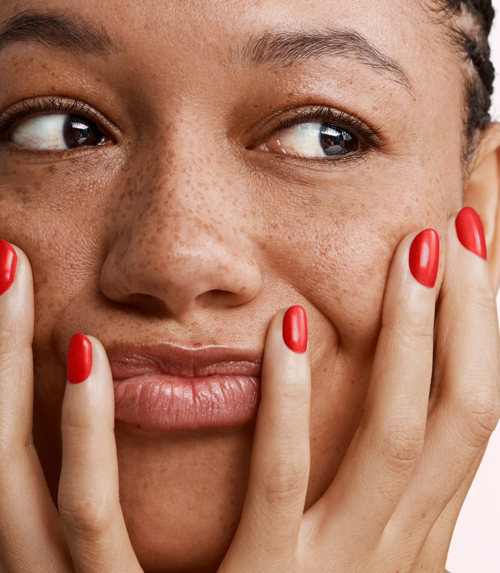 Close-up of a woman with Pink Gellac 441 Scarlet Red manicured nails near her face.