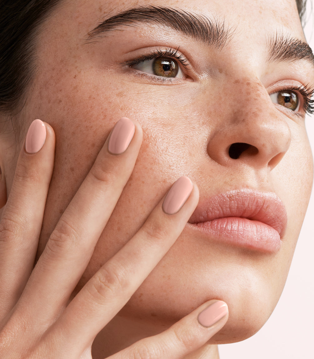 Close-up of a woman with Pink Gellac Rubber Base Cover Soft Nude manicured nails near her face.