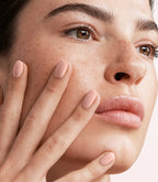 Close-up of a woman with Pink Gellac Rubber Base Cover Soft Nude manicured nails near her face.