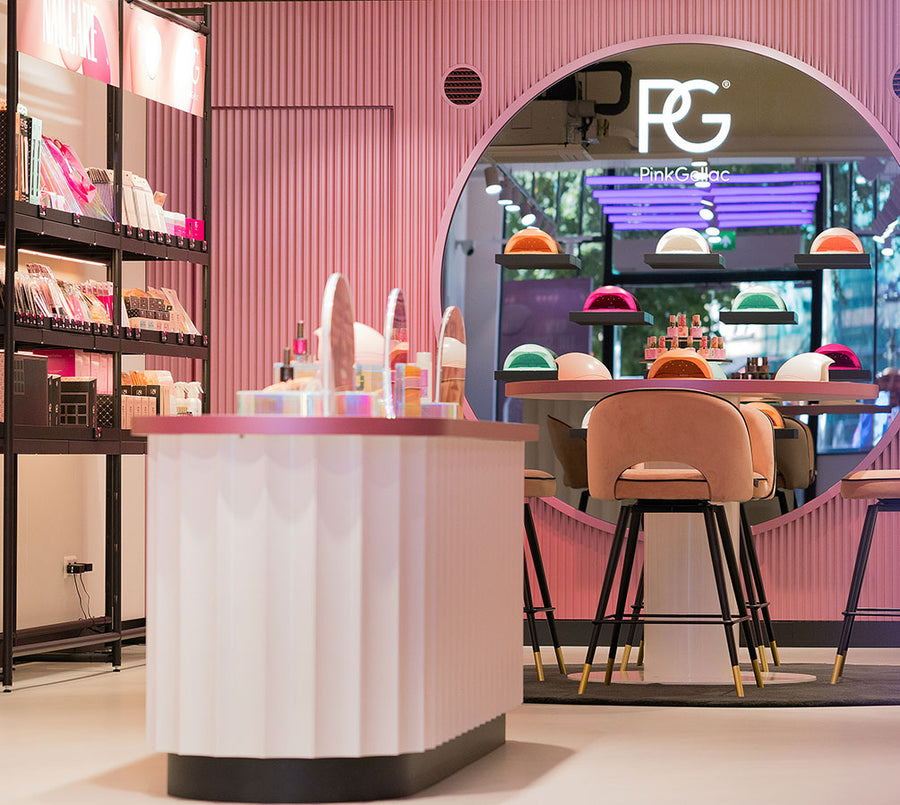 Interior of a pink shop with make-up displays and a large mirror with the logo "Pink Gellac".