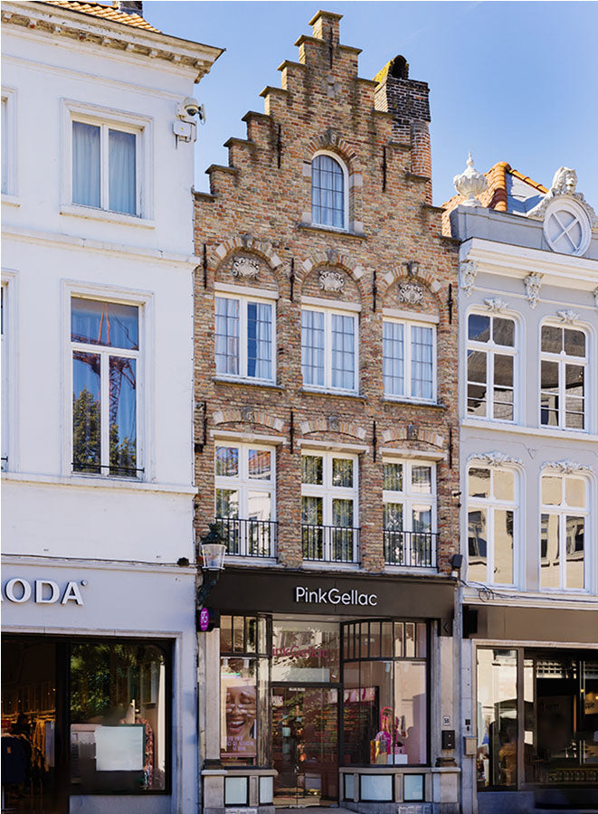 Facade of a historic building with stepped gables, a lacquer salon called Pink Gellac on the ground floor, located between two other shops.