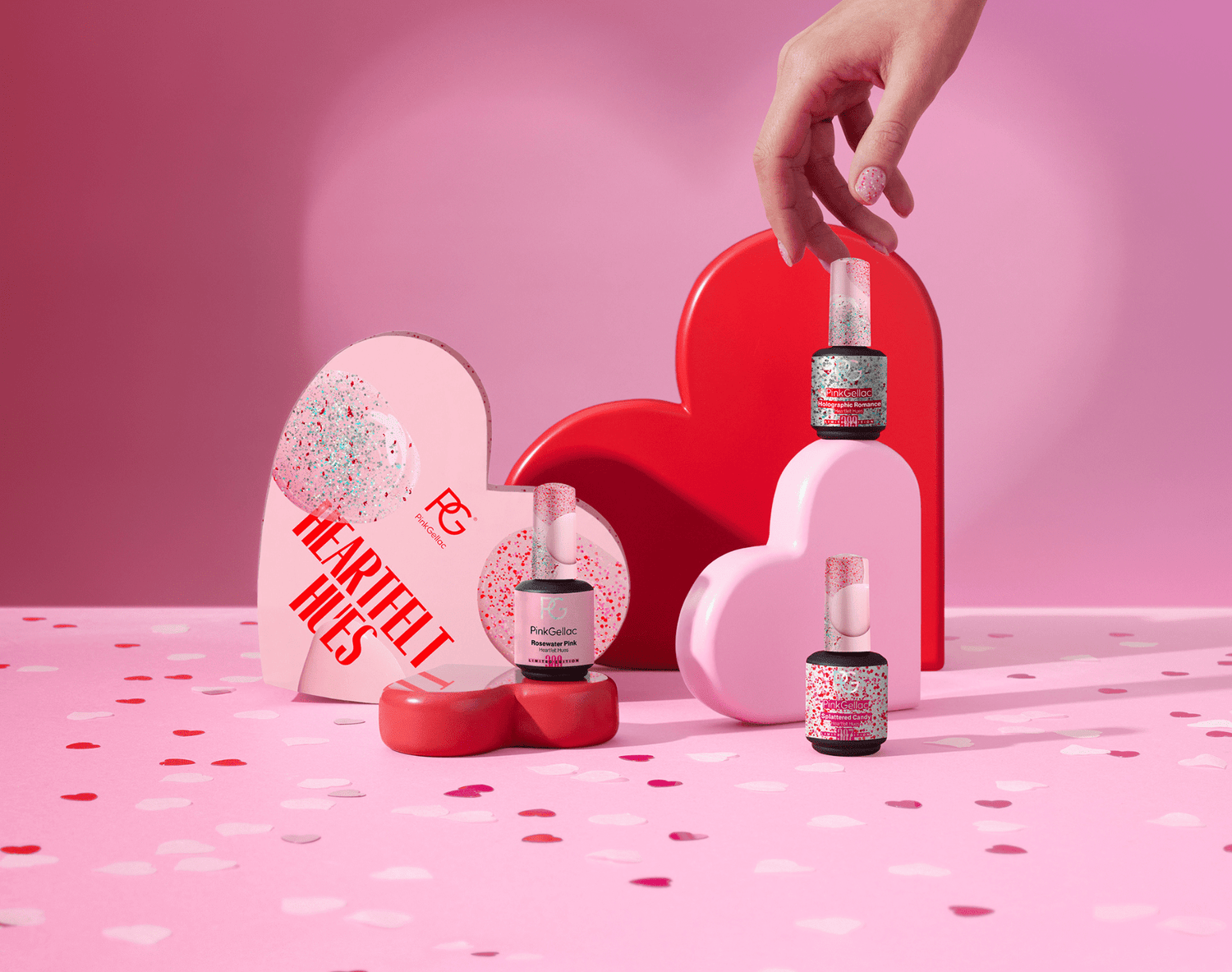 An image with pink and red heart-shaped boxes, nail polish bottles with glitter, and a hand holding a bottle on a pink background with confetti.