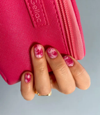 Hand with red manicured nails holding a red purse, wearing Pink Gellac 109 Lipstick Red.