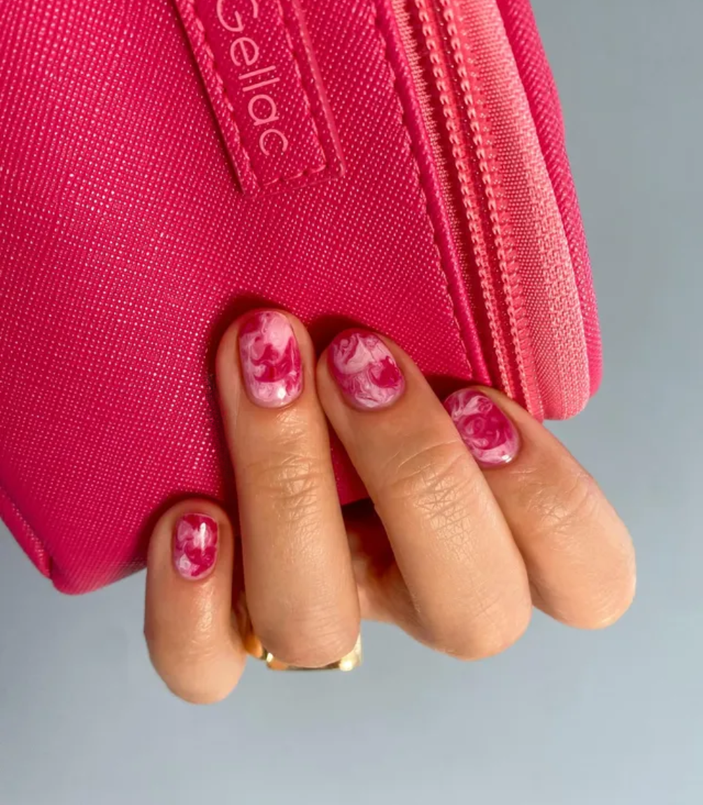 Hand with red manicured nails holding a red purse, wearing Pink Gellac 109 Lipstick Red.