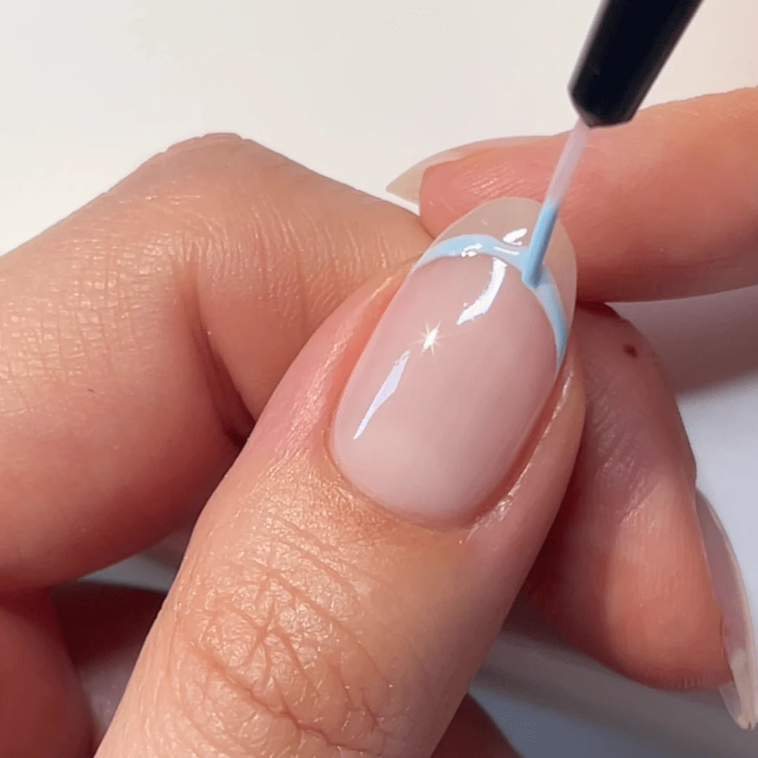 A hand that has a nail with a French manicure, where the nail edge is painted with a light blue nail polish.