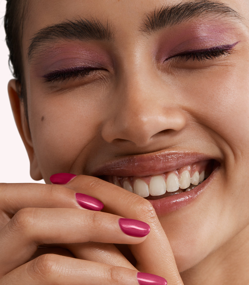 Close-up of a woman with Pink Gellac 170 Powerful Plum manicured nails near her face.