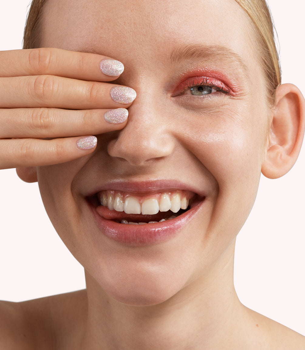 Close-up of a woman with Pink Gellac 204 Diamond Silver manicured nails near her face.