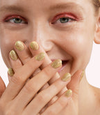 Close-up of a woman with Pink Gellac 236 Gossip Gold manicured nails near her face.
