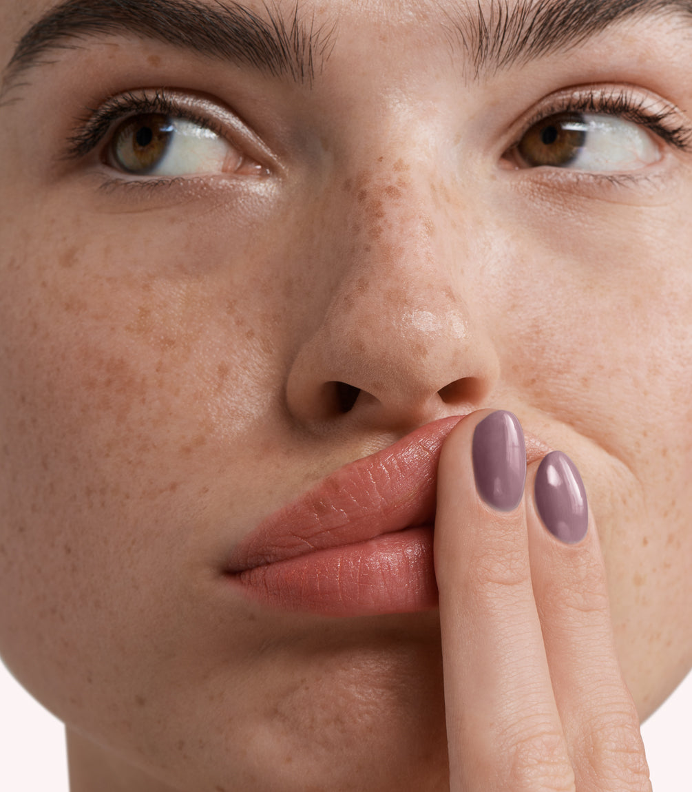Close-up of a woman with Pink Gellac 280 Desert Lila manicured nails near her face.
