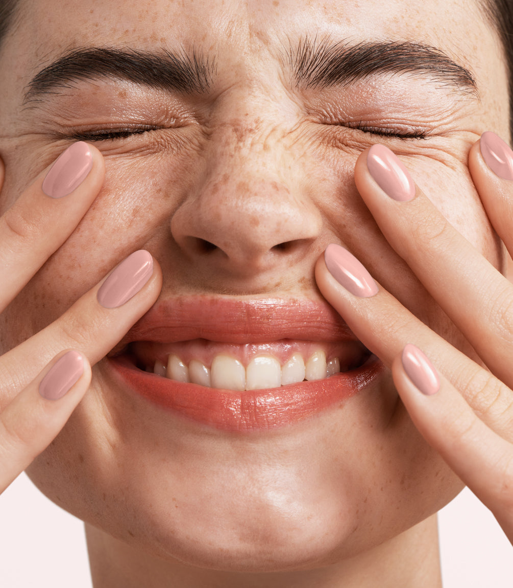 Close-up of a woman with Pink Gellac Rubber Base Cover Rose Beige manicured nails near her face.
