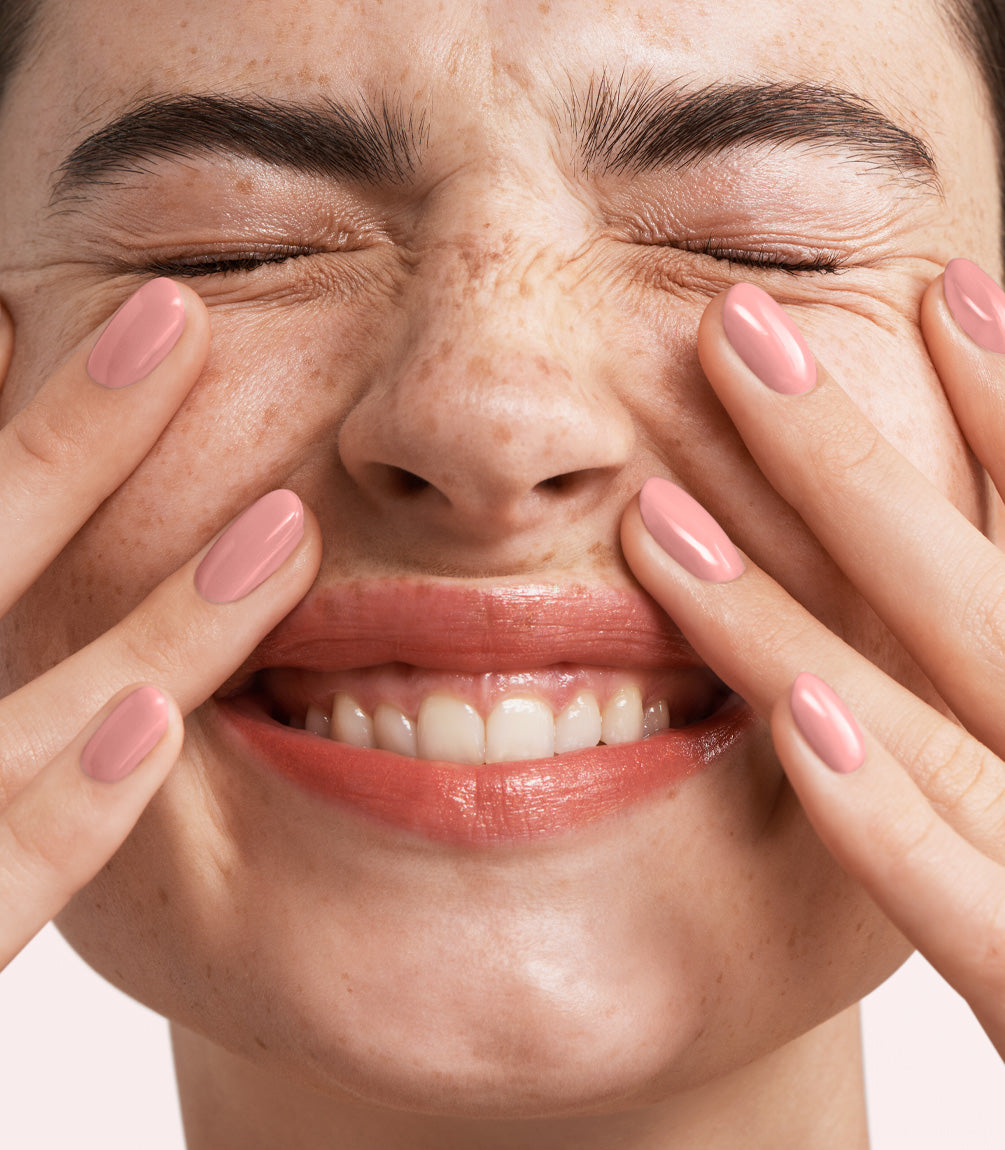 Close-up of a woman with Pink Gellac Build it Base Flawless Rose manicured nails near her face.
