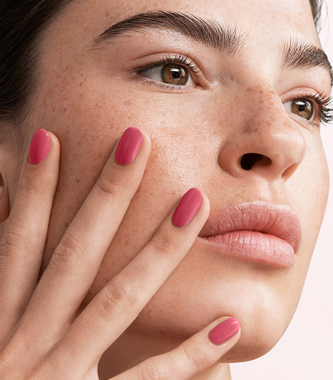 Close-up of a woman with Pink Gellac 103 Pepper Pink manicured nails near her face.