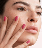 Close-up of a woman with Pink Gellac 103 Pepper Pink manicured nails near her face.