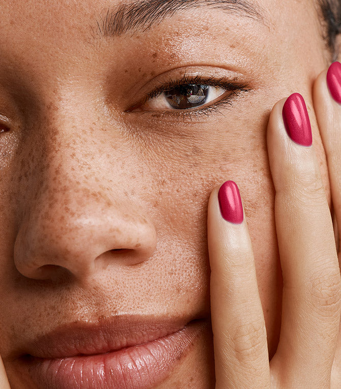 Close-up of a woman with Pink Gellac 104 Passion Pink manicured nails resting against her face.