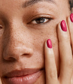 Close-up of a woman with Pink Gellac 104 Passion Pink manicured nails resting against her face.