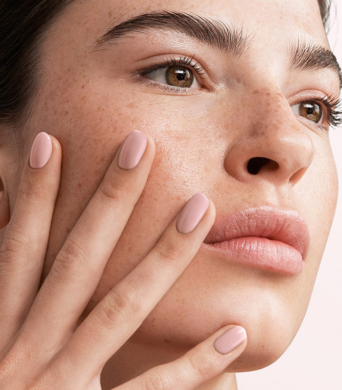 Close-up of a woman with Pink Gellac 105 Blush Orange manicured nails near her face.