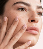 Close-up of a woman with Pink Gellac 105 Blush Orange manicured nails near her face.