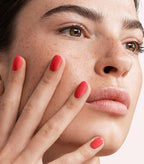 Close-up of a woman with Pink Gellac 107 Cheerfull Red manicured nails near her face.