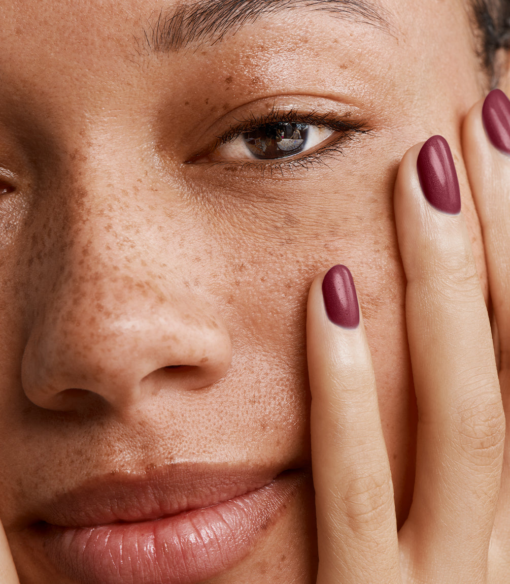 Close-up of a woman with Pink Gellac 111 Rustic Red manicured nails near her face.