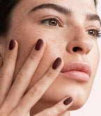 Close-up of a woman with Pink Gellac 112 Chique Red manicured nails near her face.