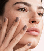 Close-up of a woman with Pink Gellac 113 Intens Taupe manicured nails near her face.