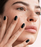 Close-up of a woman with Pink Gellac 120 Beautiful Black manicured nails near her face.