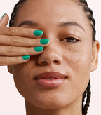 Close-up of a woman with Pink Gellac 124 Caribbean Blue manicured nails near her face.
