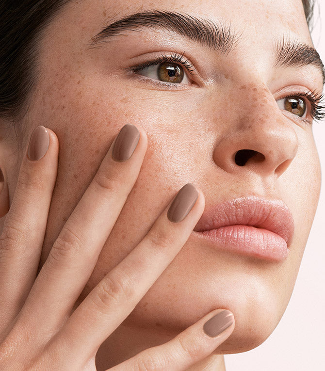 Close-up of a woman with Pink Gellac 139 Natural Taupe manicured nails near her face.