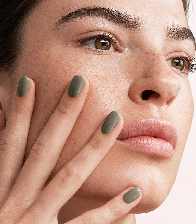 Close-up of a woman with Pink Gellac 140 Asphalt Grey manicured nails near her face.