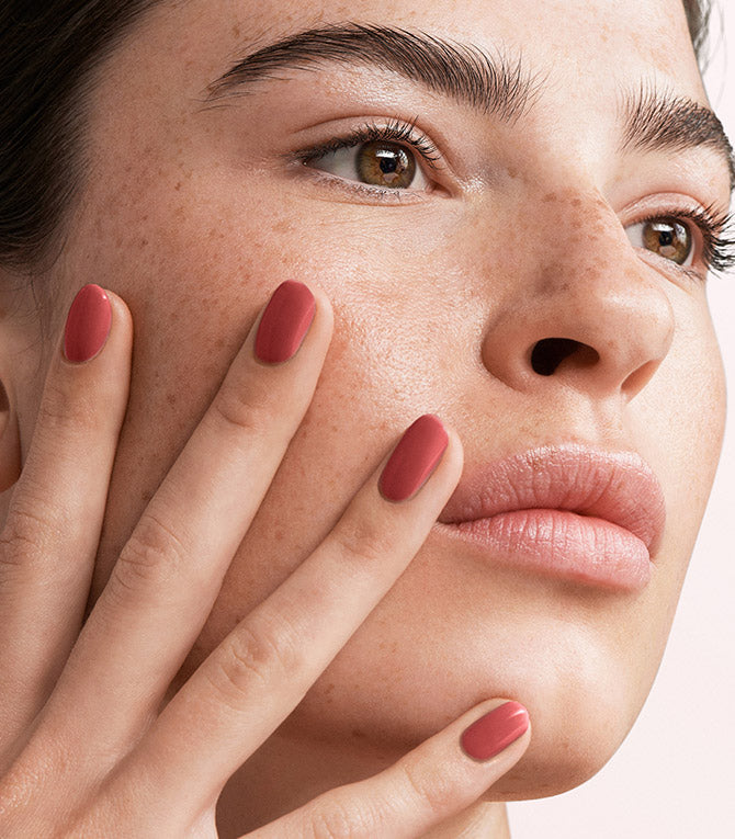 Close-up of a woman with Pink Gellac 142 Coral Red manicured nails near her face.