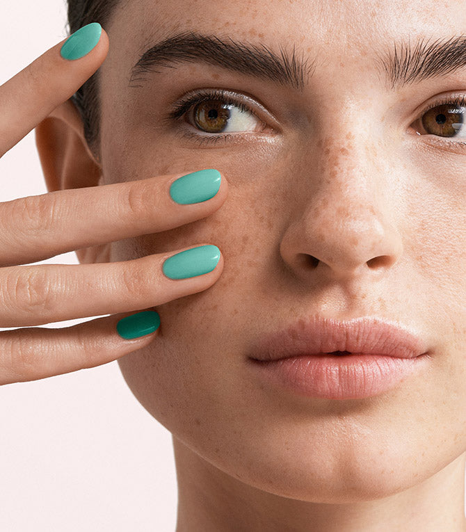 Close-up of a woman with Pink Gellac 145 Seafoam Blue manicured nails near her face.