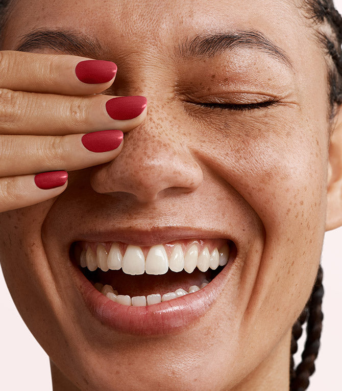 Close-up of a woman with Pink Gellac 149 Moulin Red manicured nails near her face.