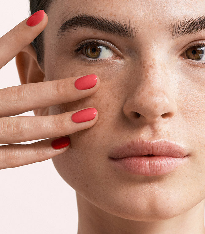 Close-up of a woman with Pink Gellac 156 Tropical manicured nails near her face.
