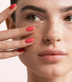Close-up of a woman with Pink Gellac 156 Tropical manicured nails near her face.